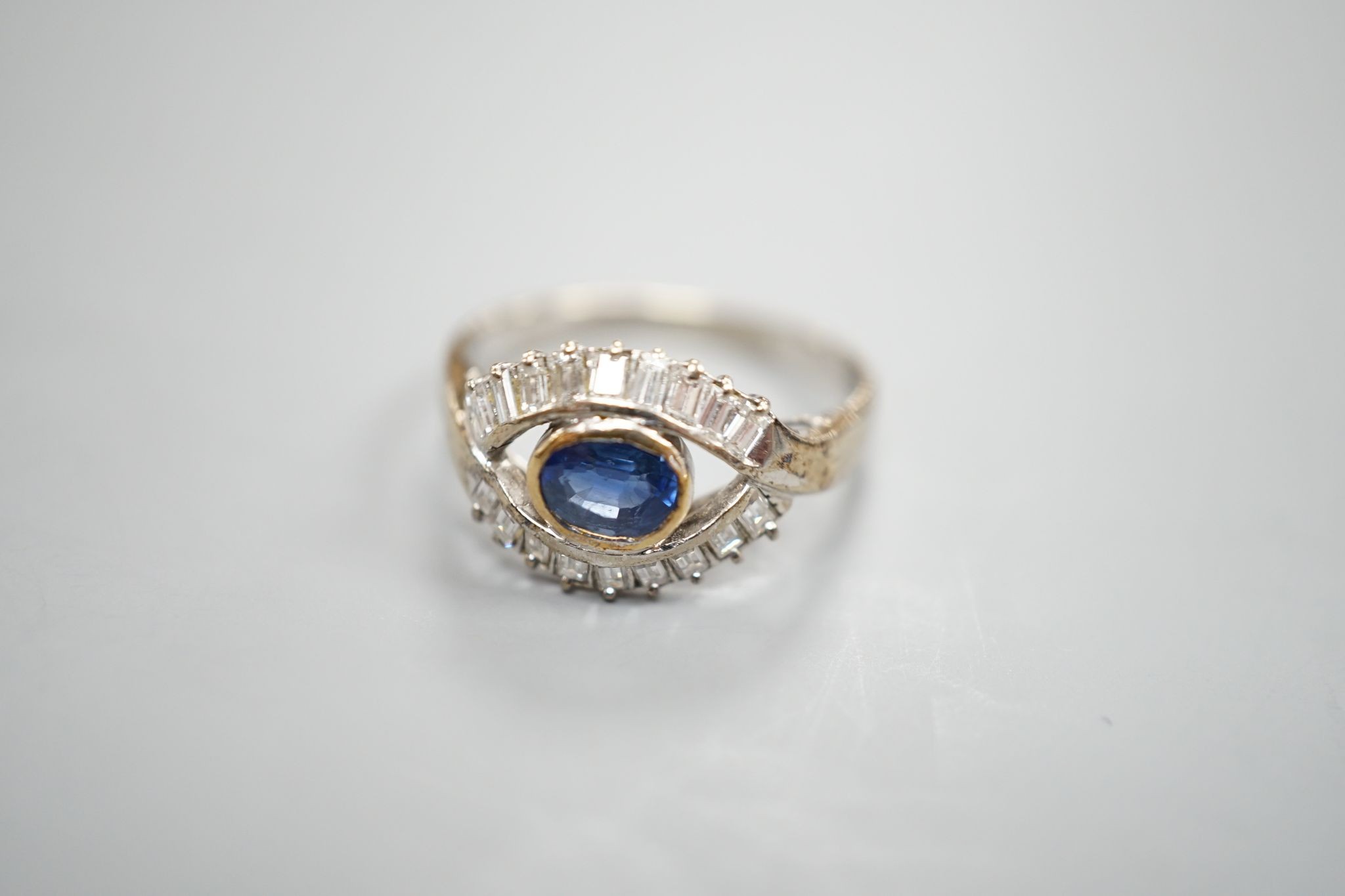 A modern 585 white metal sapphire and baguette cut diamond cluster set 'eye' ring, size T, gross 4 grams.
